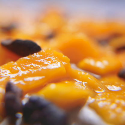 Close-up of a chocolate cake with pieces of mango and a drizzle of sauce on top.